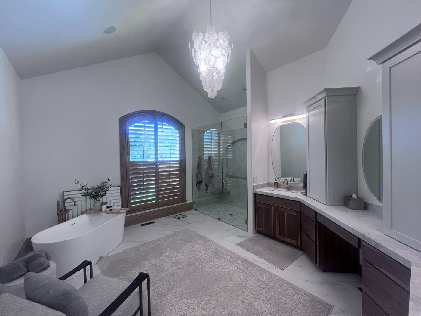 Primary bathroom with a freestanding tub, an arched window and a long vanity