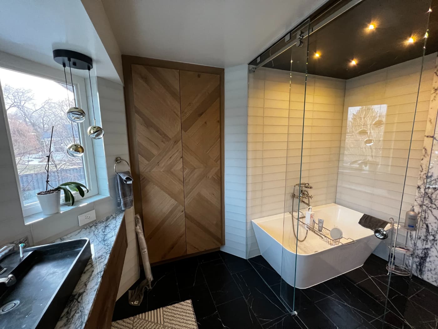 Bathroom with a freestanding tub, shiplap walls, a glass shower and black tile floor