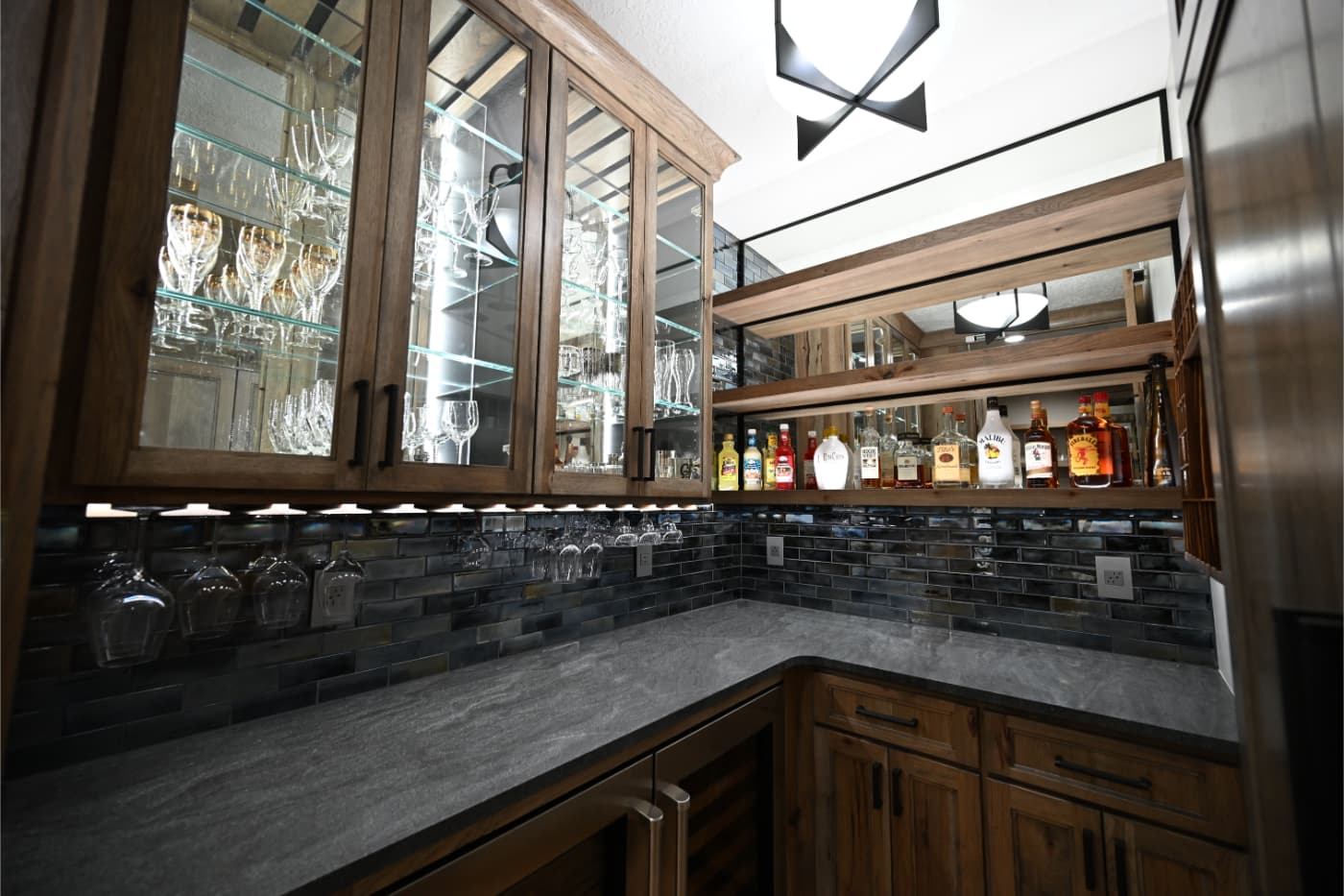 Wet bar with glass-front cabinets, a wine glass rack and a slate tile backsplash