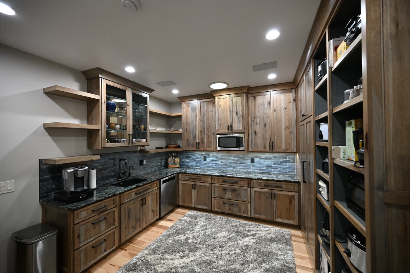 Rustic wood kitchen with glass-front uppers, floating shelves and a pantry wall