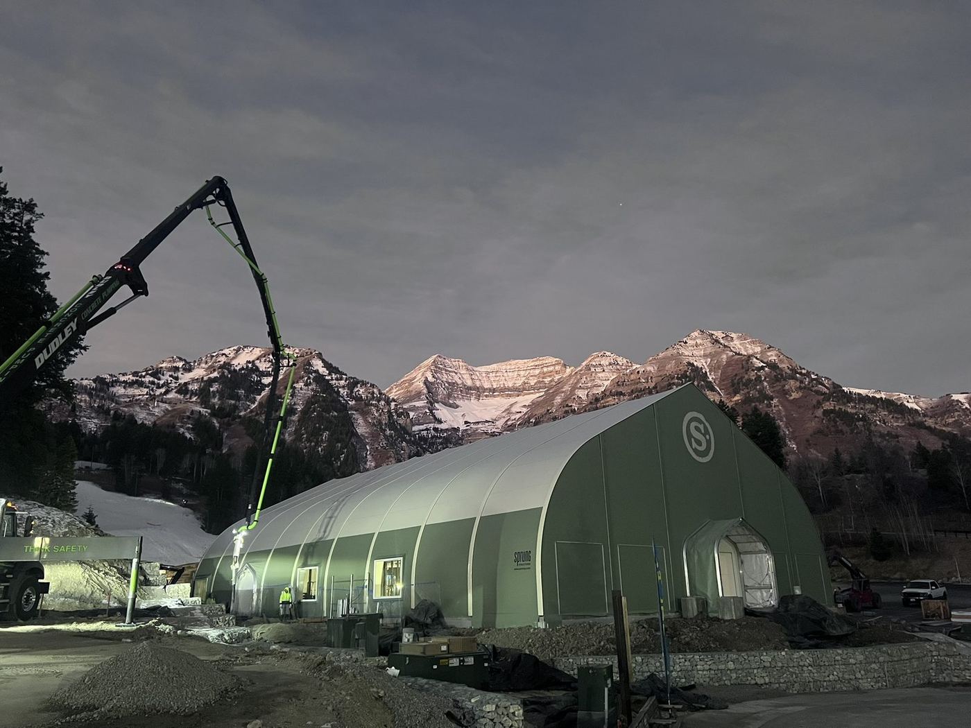 Completed fabric structure lit at night beneath the mountains