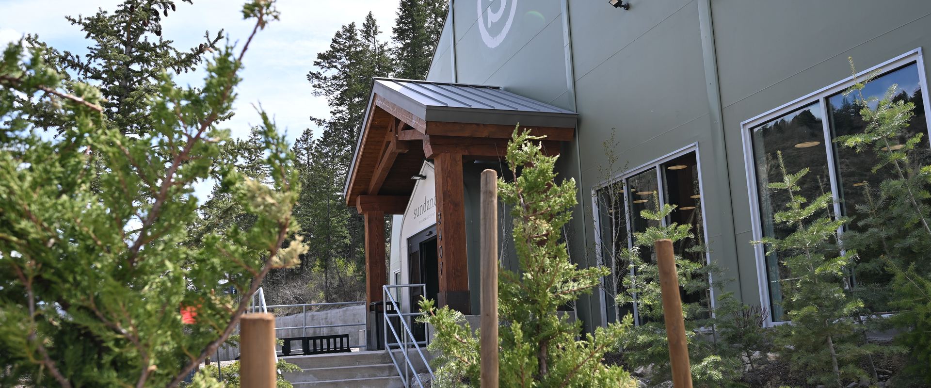 Resort lodge entry with timber stairs beneath the mountains