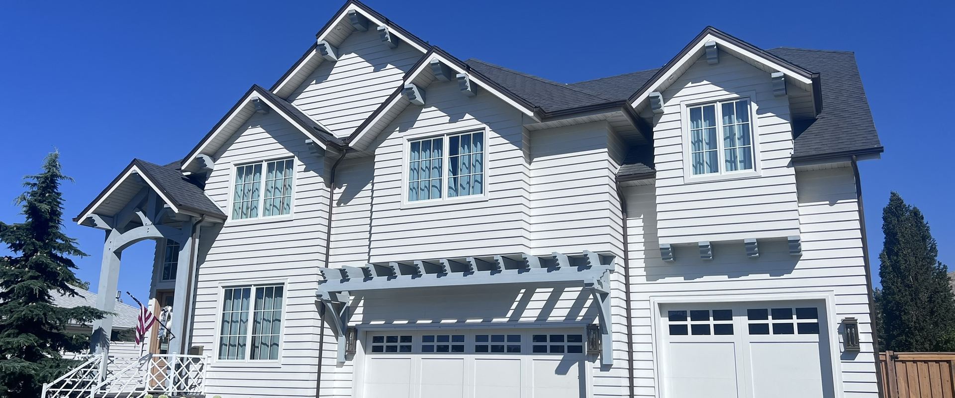 Home exterior with new white lap siding and a pergola
