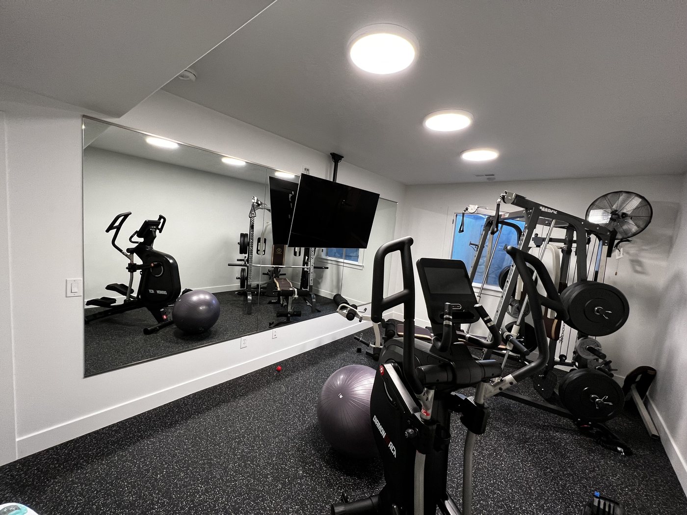 Finished basement home gym with rubber flooring and mirrored wall
