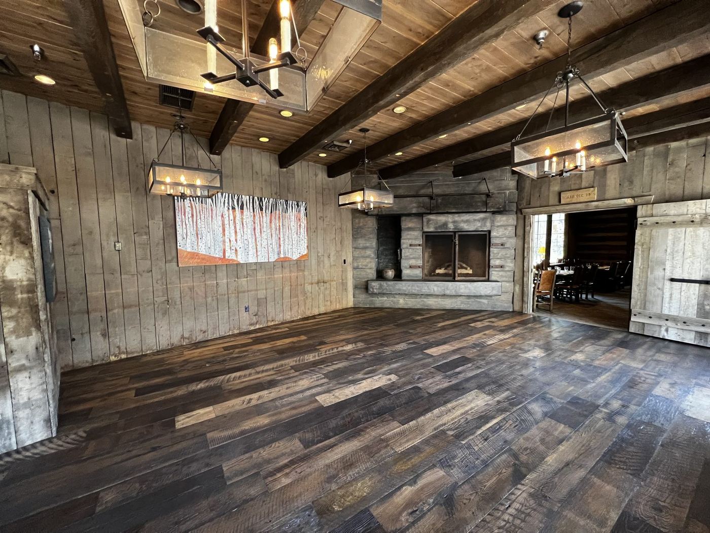 Rustic lodge interior with reclaimed wood walls, floors and a stone fireplace